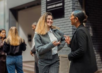 Deux jeunes femmes devant une écoles de tourisme discutent ensemble